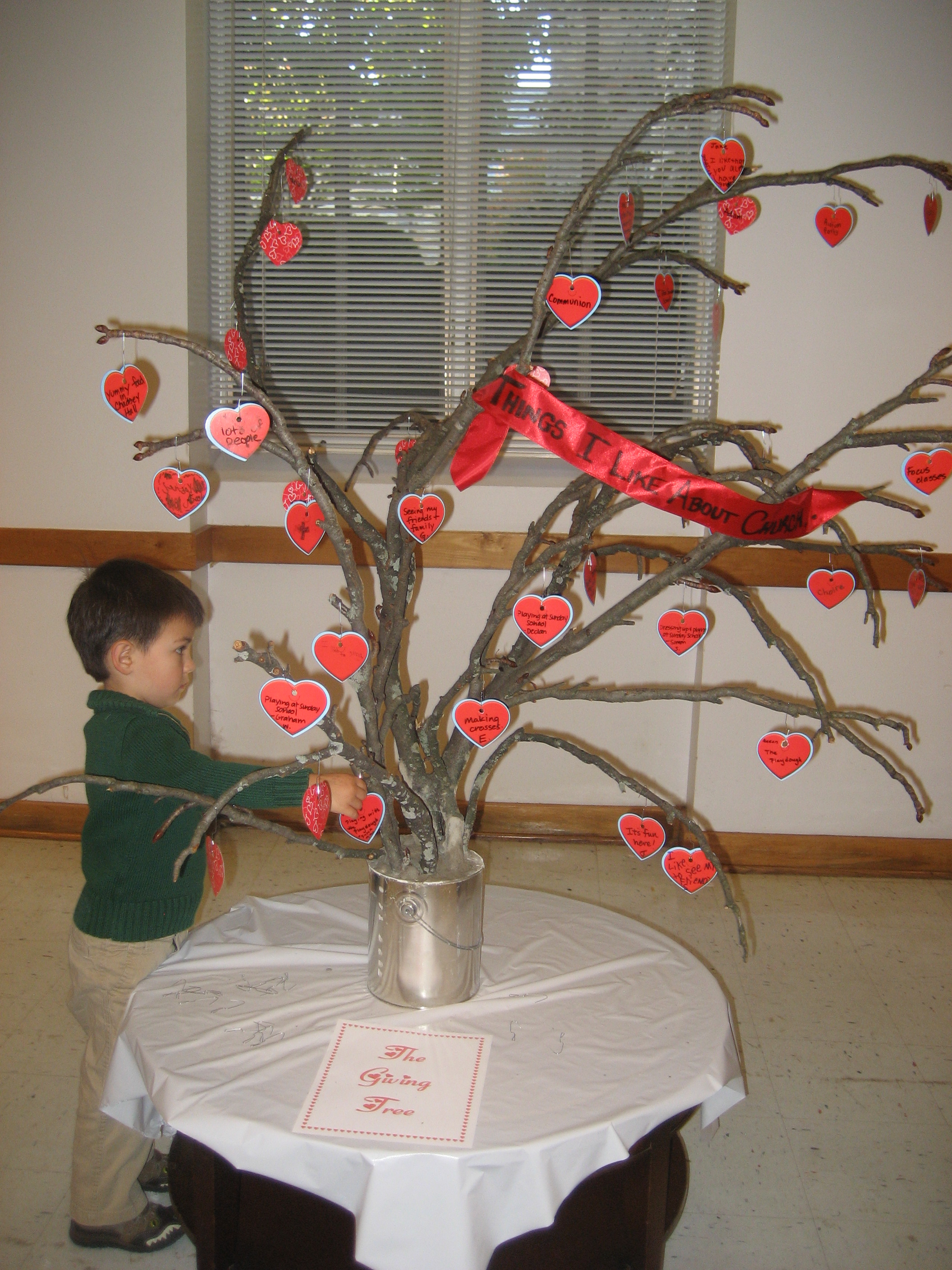 Child hangs a heart on the Giving Tree